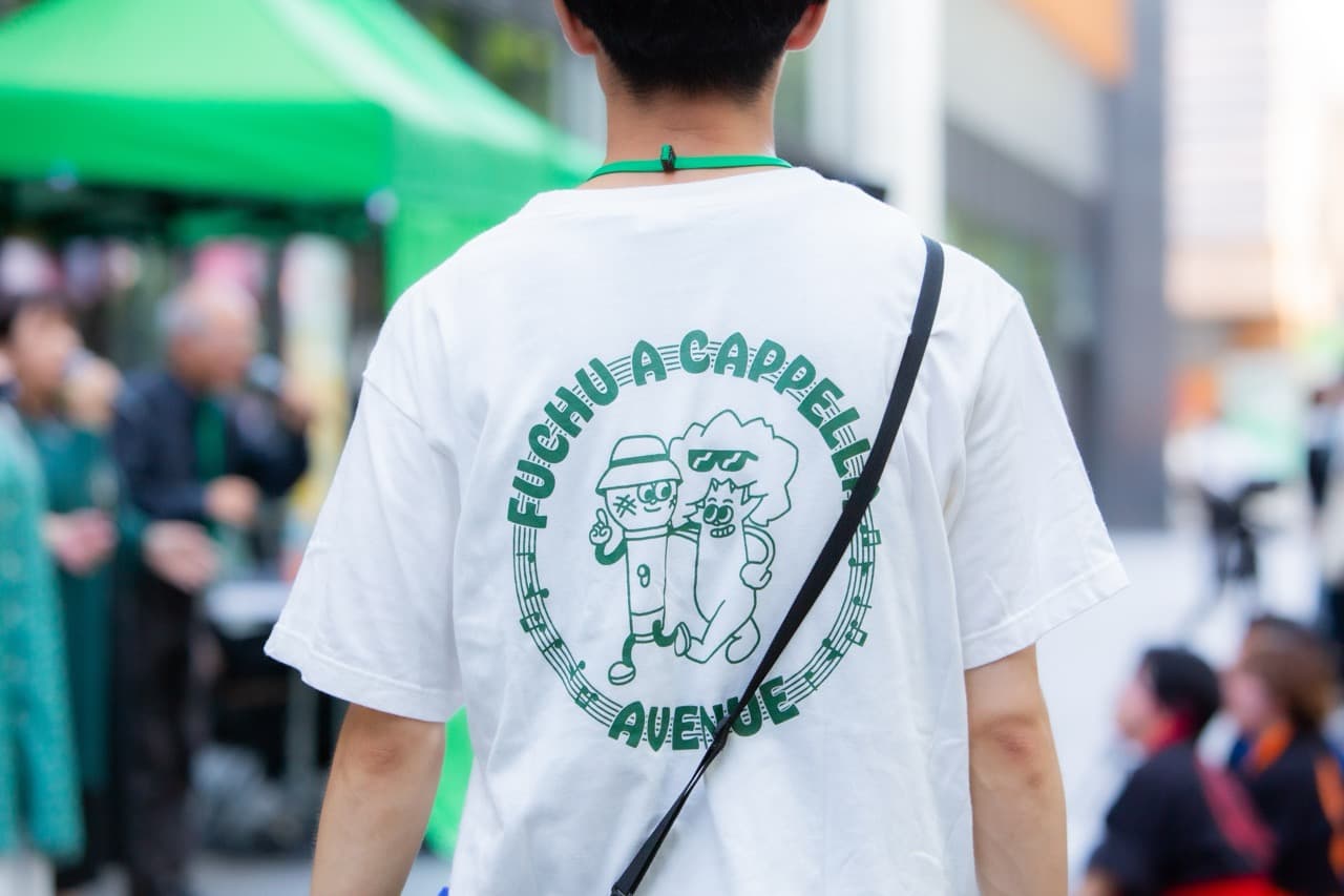 Fuchu A Cappella Avenue 公式Tシャツの背中。グリーンのロゴと2体のマスコット
